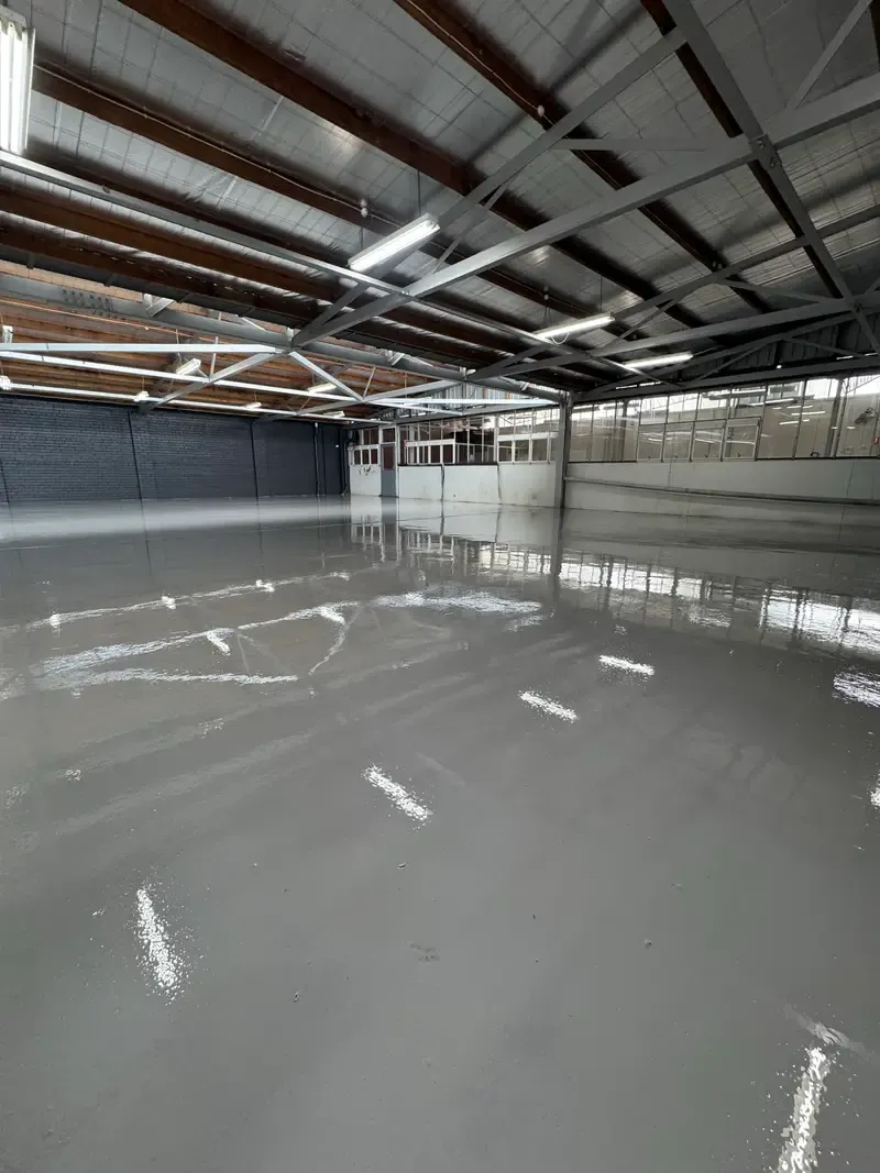 Second view of the finished grey epoxy floor in the Oakleigh warehouse, looking towards the internal office windows